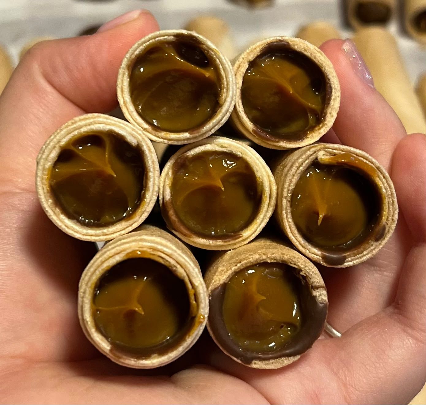 Mano sosteniendo seis barquillos rellenos de manjar